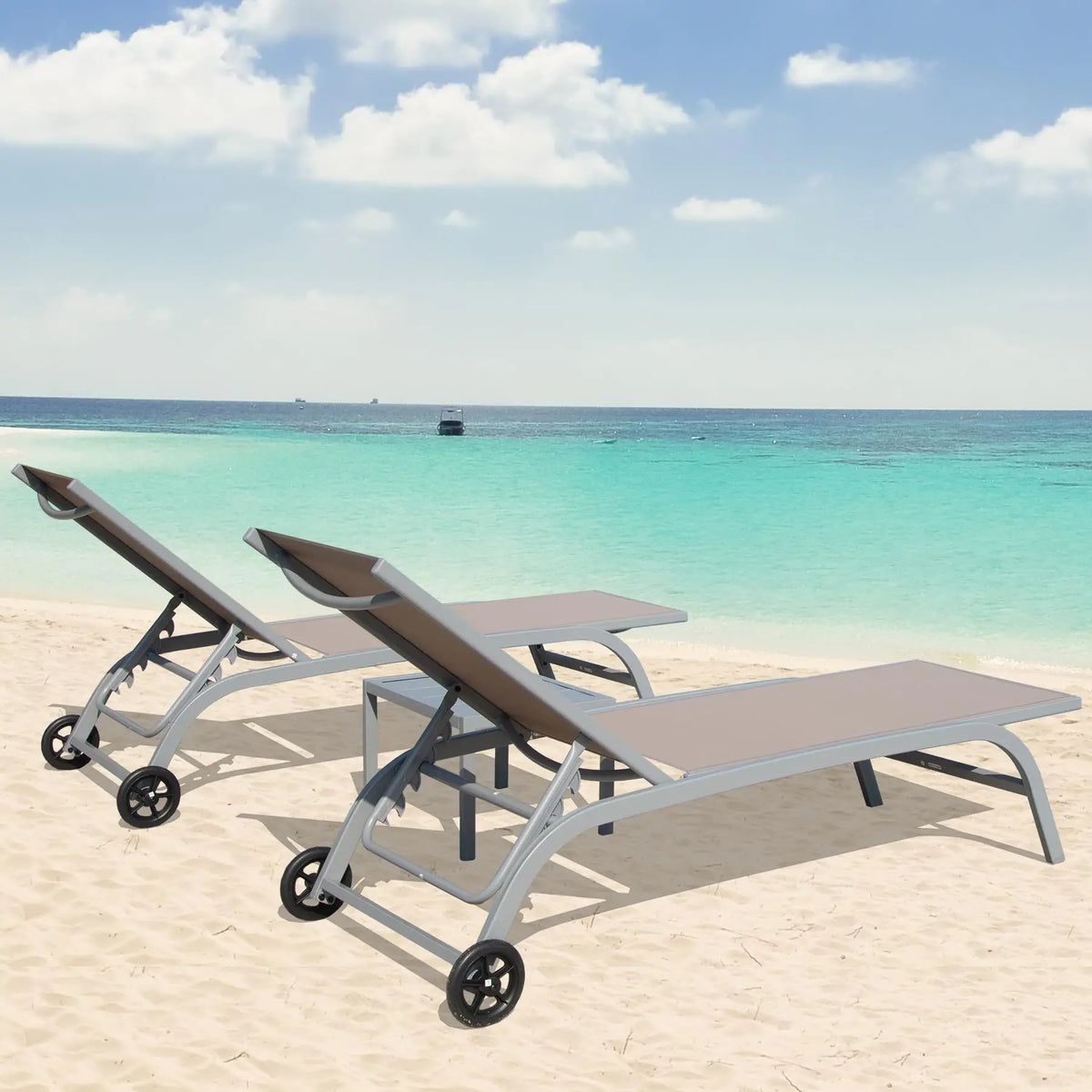 Two aluminum chaise loungers with table, brown fabric, angled on sandy beach near turquoise water