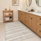 Beige and cream striped area rug on tiled bathroom floor near wooden vanity