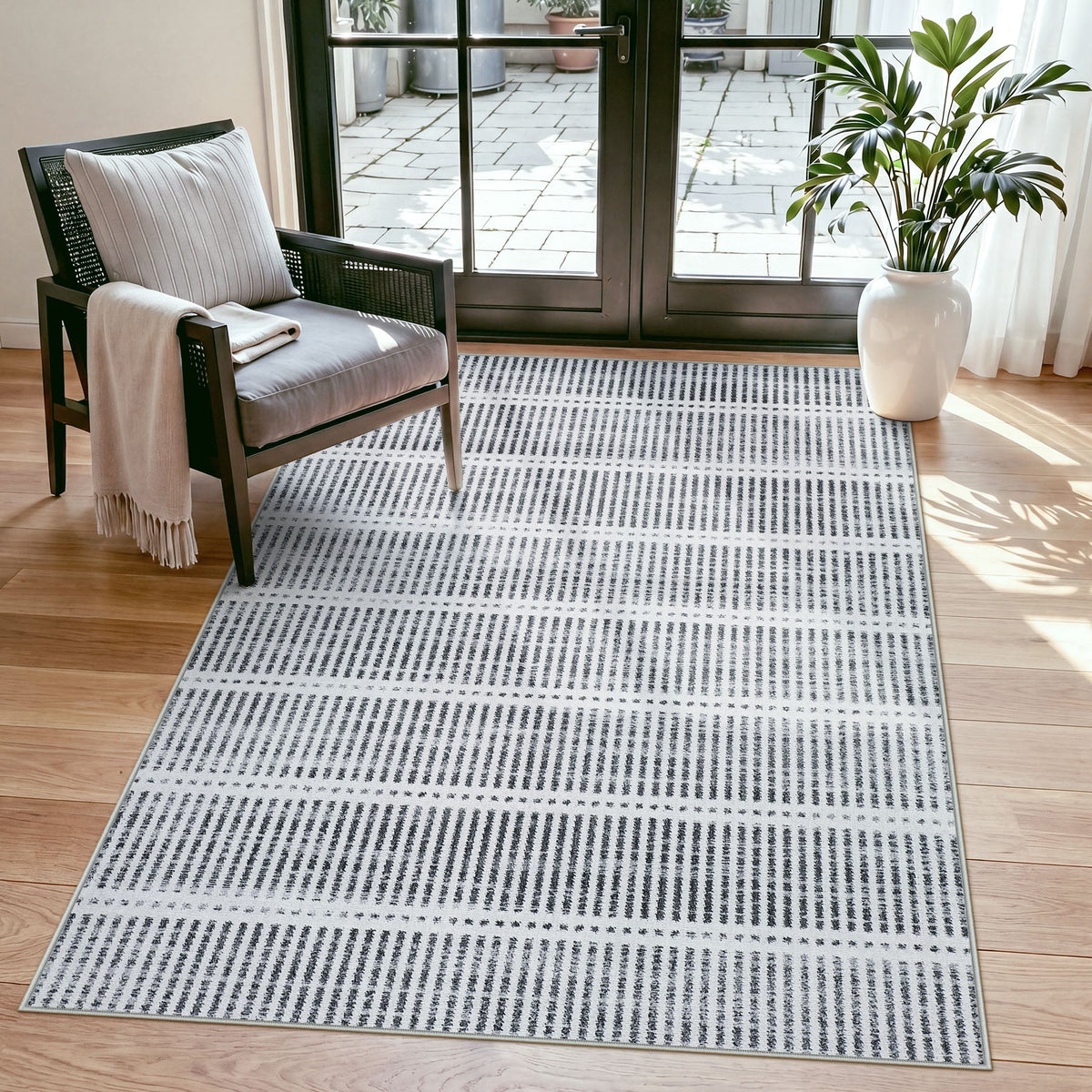 Black and white striped area rug on hardwood floor near chair and glass door