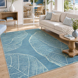 Blue leaf pattern area rug on wooden floor in living room with sofa and side table