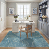 Blue leaf pattern area rug on wooden floor in a sunlit home office with white desk and chair
