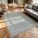 Scalloped grey area rug with white checkered border on wooden floor in living room