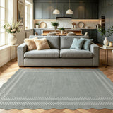 Scalloped grey area rug with white geometric border on wooden floor in living room