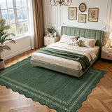 Scalloped green area rug with geometric border on wooden floor in bedroom