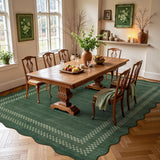 Scalloped green area rug with white geometric pattern on wooden floor in dining room