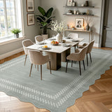 Scalloped light grey area rug with white geometric border on wooden floor in dining room