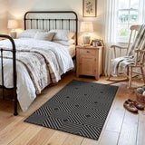 Black and white geometric patterned jute rug on wooden floor in bedroom