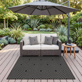 Black and white geometric patterned jute rug on wooden deck under patio umbrella