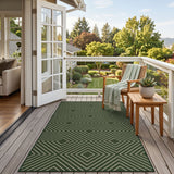 Dark green geometric patterned jute rug on wooden deck with outdoor furniture and garden view