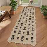 Black floral pattern on beige jute runner rug on wooden floor near plants and door