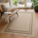 Beige scalloped jute rug with brown border on wooden floor near chair and plants
