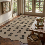 Black floral pattern on beige jute rug on hardwood floor near wooden table and garden door