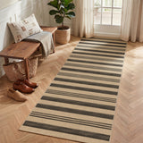 Striped jute runner rug in beige and dark gray on light wood floor near bench and shoes