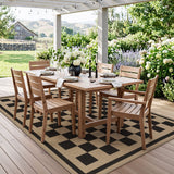 Black and beige checkered jute rug on wooden deck under pergola with outdoor dining set