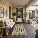 Beige jute runner rug with black floral pattern on dark wood deck in outdoor patio setting