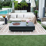 Dark grey rectangular fire pit table with circular burner, on patterned rug outdoors near sofa