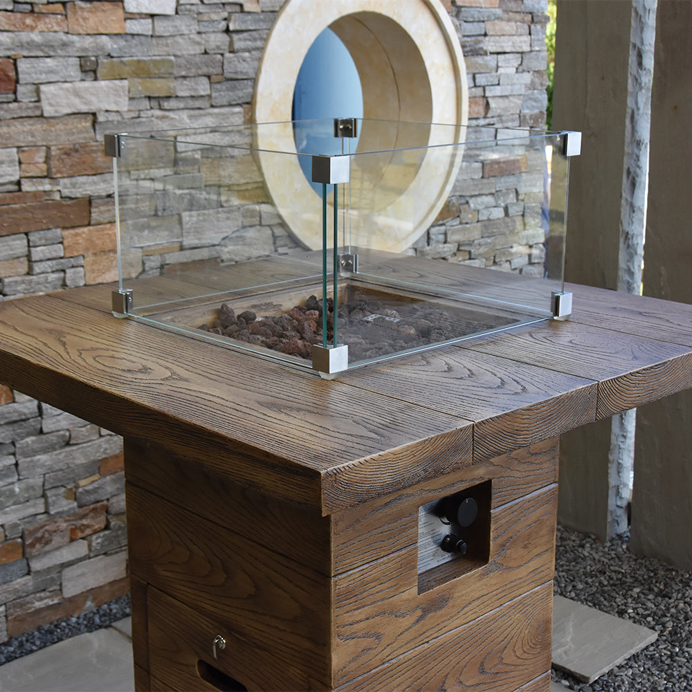 Tempered clear glass wind screen on a wooden fire pit, angled view against stone wall