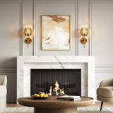 Brass wall sconce with smoky gray glass shade, shown in a living room with fireplace