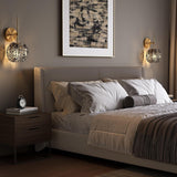 Brass wall sconce with smoky gray glass shade, shown in a bedroom setting
