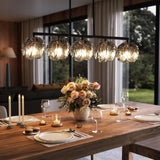 Five-light linear chandelier with smoky gray glass shades and matte black frame, hanging over a wooden dining table