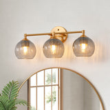 Gold bathroom vanity light with three gray crackle glass shades mounted above a mirror
