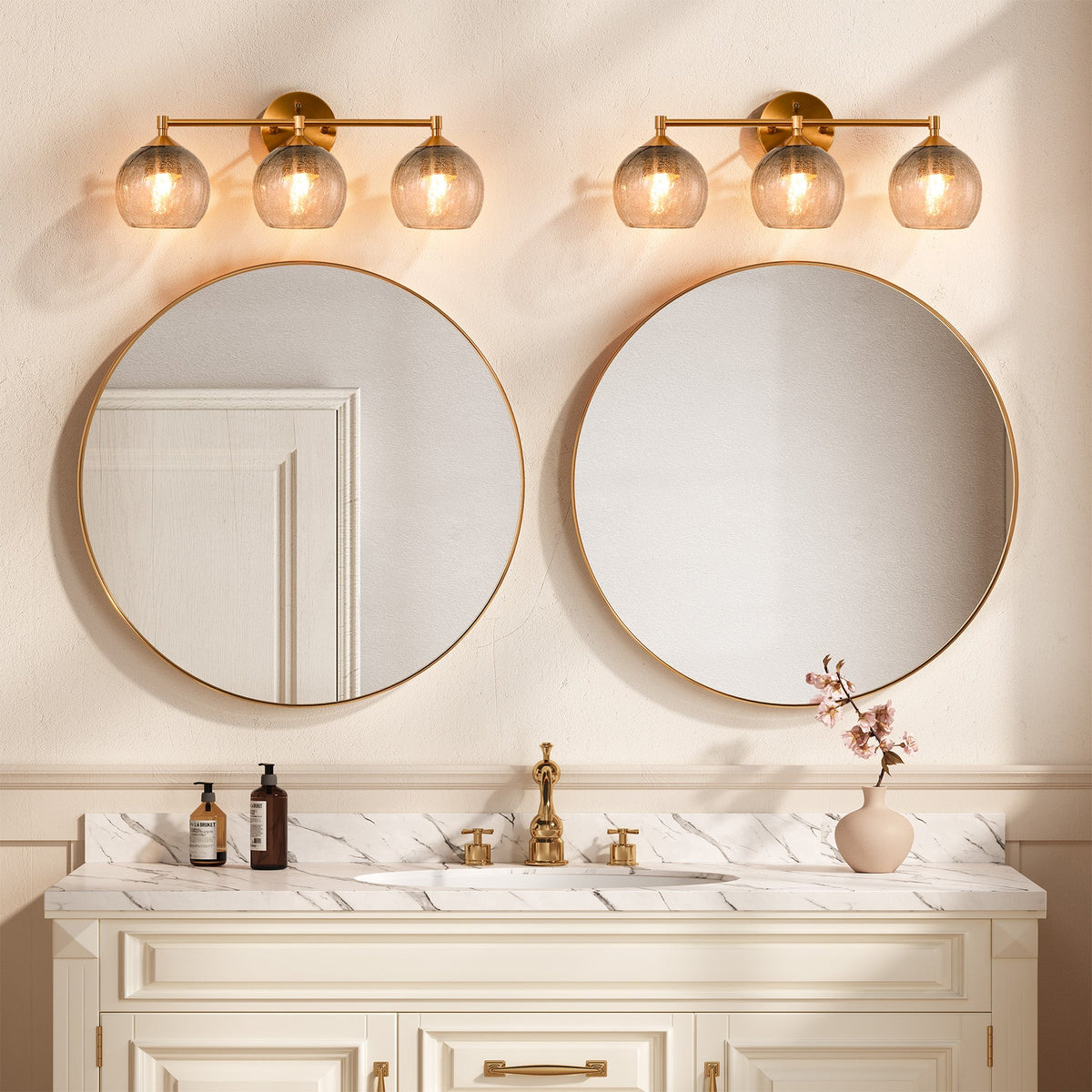 Gold bathroom vanity light with three gray crackle glass shades mounted above round mirrors