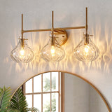 Three-light bathroom vanity light with gold finish and textured glass shades mounted above a mirror