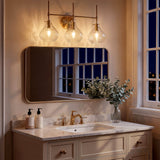 Three-light bathroom vanity light with gold finish and water ripple glass shades, mounted above a mirror in a beige vanity room