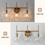 Three-light bathroom vanity light with gold finish and textured glass shades, light on