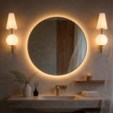 Gold double-headed wall sconce with milky white shades mounted on bathroom wall