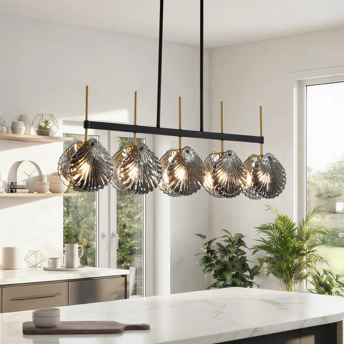 Five-light linear chandelier with smoky gray shell glass shades, black frame, and gold accents, hanging over a kitchen island