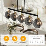 Five-light linear chandelier with smoky gray shell glass shades, black frame, and gold accents, shown in a modern kitchen setting