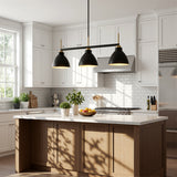 Three-light linear kitchen island light with black and gold dome shades, shown hanging over a wooden island in a bright kitchen