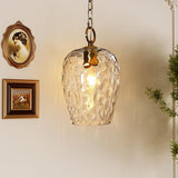 Gold hammered glass pendant light with adjustable chain, hanging in a room with framed art and greenery