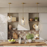 Three gold hammered glass pendant lights with adjustable chains hanging over a kitchen island
