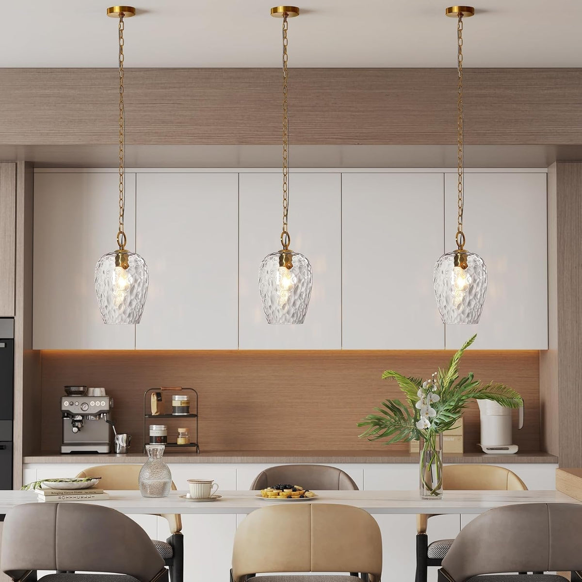 Three gold pendant lights with hammered glass shades hang over a dining table in a modern kitchen