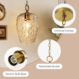 Gold hammered glass pendant light with adjustable chain and ceramic bulb base, shown in a room setting
