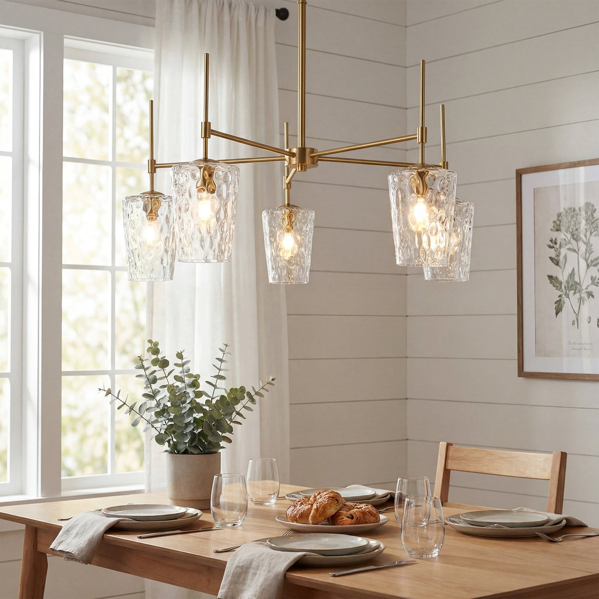 Brushed gold chandelier with water ripple glass, hanging over a wooden dining table