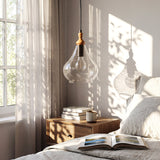 Teardrop pendant light with seeded glass and wood accent hanging over a wooden nightstand in a bedroom