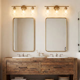 Gold bathroom vanity light with three bubble glass shades mounted above mirrors