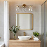 Gold bathroom vanity light with three bubble glass shades mounted above a mirror