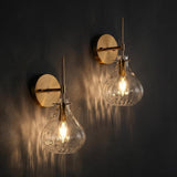 Two gold wall sconces with hammered glass shades mounted on a dark wall