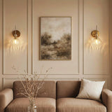 Two gold wall sconces with hammered glass shades mounted on a paneled wall above a sofa