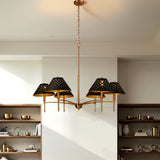 Six-light chandelier with matte black shades and gold frame hanging in a room with wooden shelves