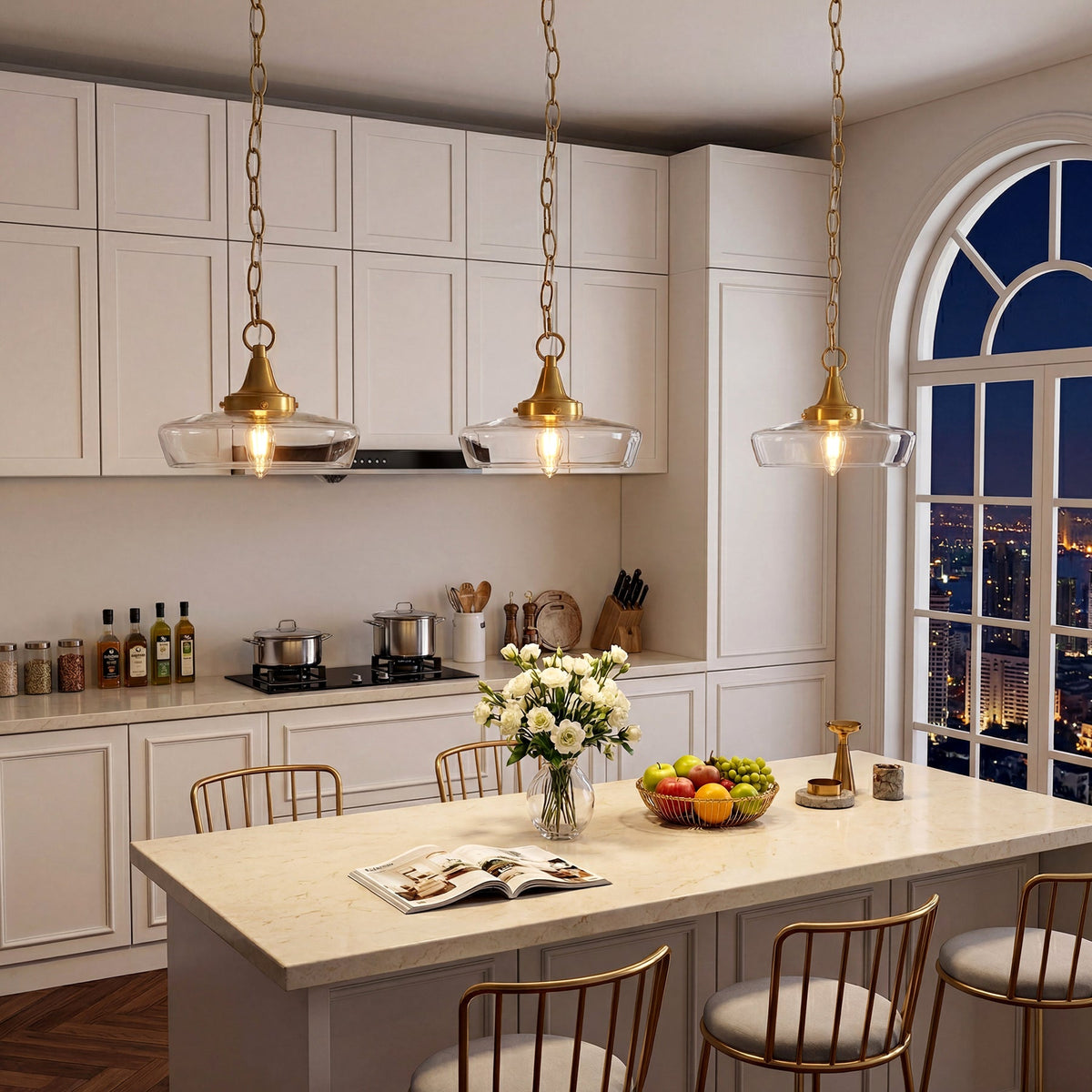 Three gold pendant lights with clear glass shades hang over a kitchen island at night