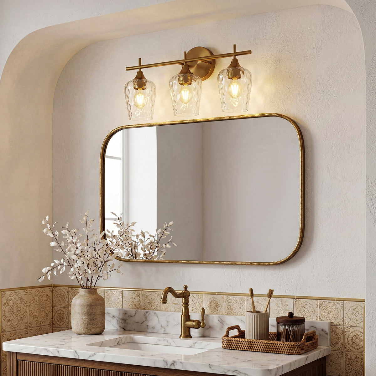 Brushed brass three-light vanity fixture with water ripple glass shades above a bathroom mirror