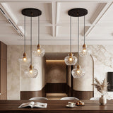 Black and gold three-light pendant with water ripple glass shades, shown from a low angle over a dining table