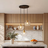 Black and gold three-light pendant with textured glass shades hanging over a kitchen island