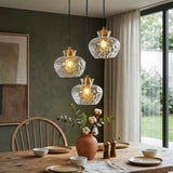Black and gold three-light pendant with textured glass shades over a wooden dining table