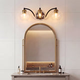 Black and brass three-light vanity fixture with clear glass globes above a bathroom mirror